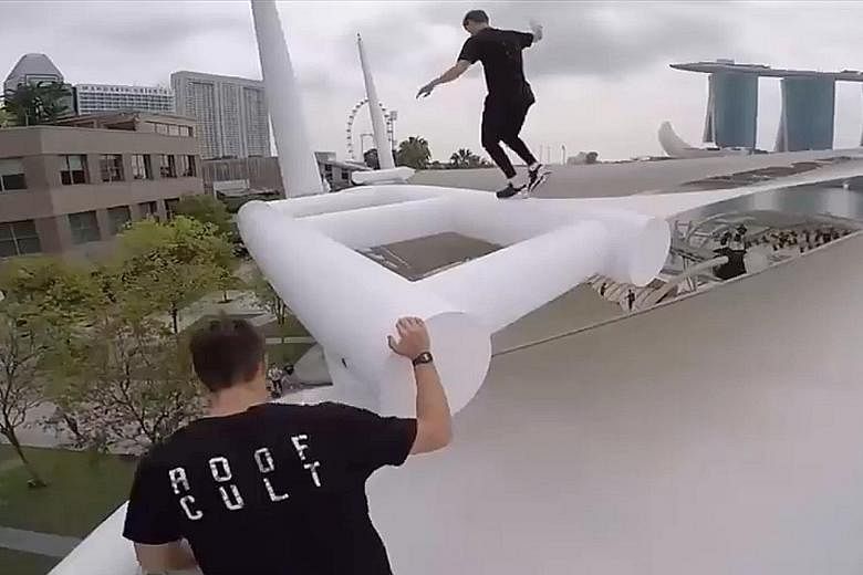 A screengrab of the men performing dangerous stunts on the roof of the Esplanade Outdoor Theatre. At least three men are seen in a Facebook video posted on Tuesday scaling the theatre's structure. They then jump, slide and balance precariously on the