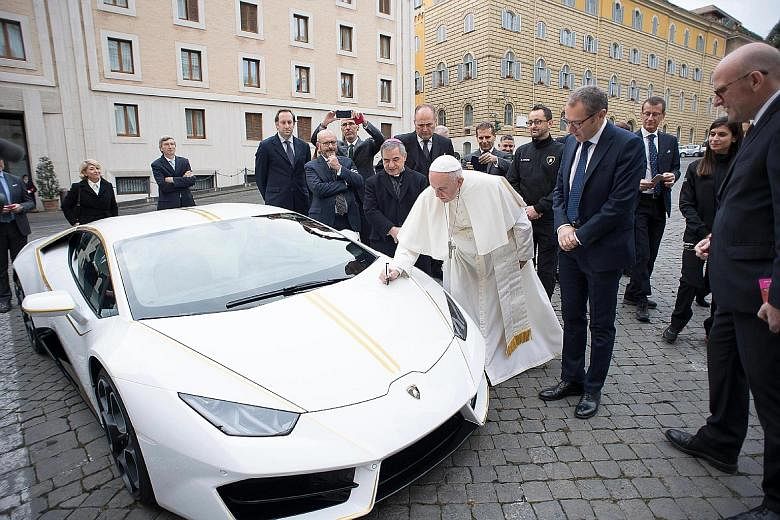 Pope Francis signing a Lamborghini Huracan in front of the pontiff's Santa Marta residence at the Vatican yesterday. Luxury sports-car maker Lamborghini had presented the Pope with a new, special edition papal-themed Huracan. According to the Catholi