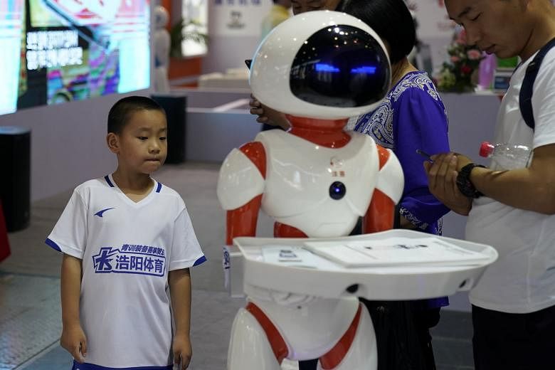 Visitors looking at a robot at the China International Robot Show in Shanghai in July. The city's plan to become an artificial intelligence hub outlines 21 measures to boost the industry.
