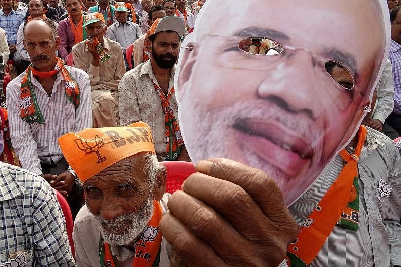 A BJP supporter holding a face mask of PM Narendra Modi at a rally earlier this month. The party raised eyebrows recently when Mr Modi reached out to DMK even though BJP has traditionally supported AIADMK in Tamil Nadu.