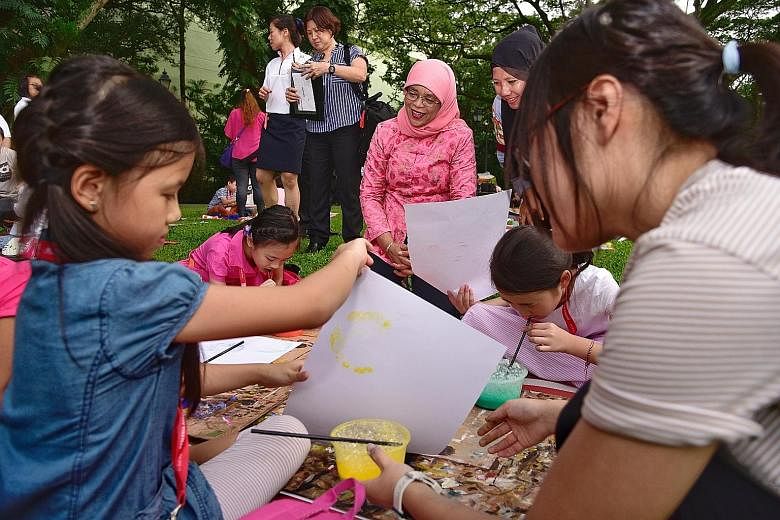 President Halimah Yacob observing children creating bubble art yesterday at the Istana. More than 30 children from the Dyslexia Association of Singapore were invited by Madam Halimah to the picnic, where they had light refreshments on the lawn and pa