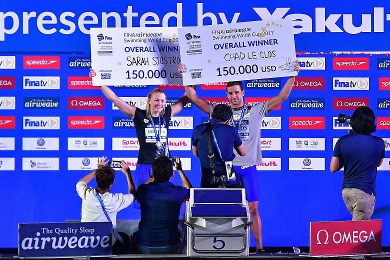 Above: Sweden's Sarah Sjostrom on her way to winning the 200m freestyle in 1min 51.63sec at the OCBC Aquatic Centre yesterday. She also won the 50m butterfly. Left: Sjostrom and Chad le Clos with their cheques after lifting the women's and men's over