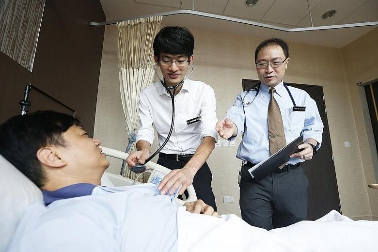 Dr Jonathan Yap (left), associate consultant in the National Heart Centre Singapore's cardiology department, seeing a patient with his mentor, Associate Professor Yeo Khung Keong, a senior consultant. The mentorship programme is among hospital scheme
