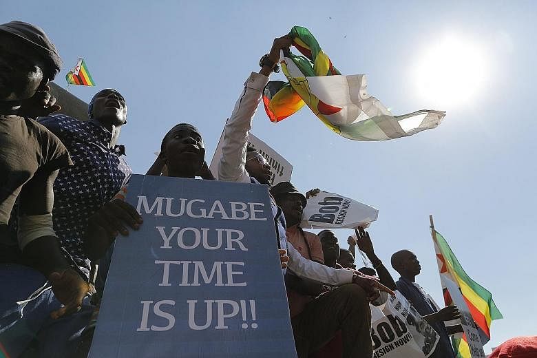 Protesters against Mr Robert Mugabe outside Parliament in Harare yesterday. Wild celebrations broke out at a joint sitting of Parliament when Speaker Jacob Mudenda announced Mr Mugabe's resignation and suspended the impeachment procedure. Protesters 