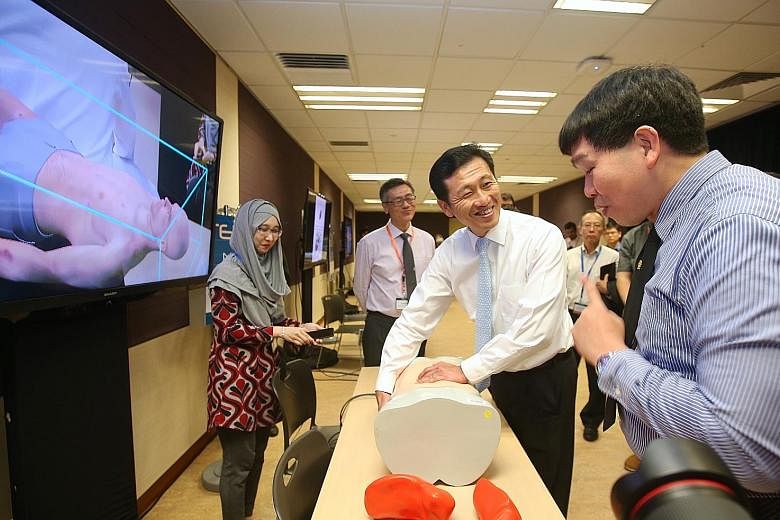 Minister Ong Ye Kung (centre) examining an interactive abdominal manikin yesterday as NUS Associate Professor Erie Lim (right) demonstrates how MediSIM, an augmented reality surgery training program, works.