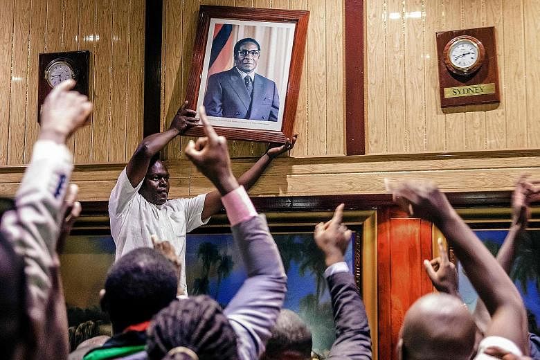 A portrait of Mr Robert Mugabe being removed from the wall at the Rainbow Towers conference centre in Harare, after his resignation on Tuesday. The portrait was torn apart and stomped to pieces by the cheering crowd, as Mr Mugabe's nearly four-decade