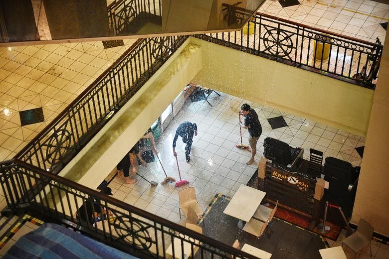 People sweeping water away from shops in the basement of Parklane Shopping Mall in Selegie Road, after a fire was extinguished by sprinklers yesterday evening. No injuries were reported, said the Singapore Civil Defence Force, which responded to the 
