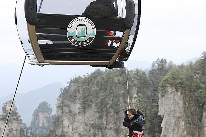 A woman hanging on to a rope from a cable car during a high-altitude mock rescue exercise yesterday at the popular tourist attraction, Zhangjiajie, located in China's Hunan province. Ropeway safety performance, emergency rescue system and rapid respo
