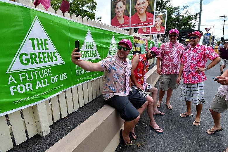 People posing for selfies outside a polling booth in Brisbane yesterday. Labor and the Greens performed strongly in big metropolitan areas in the south-east.