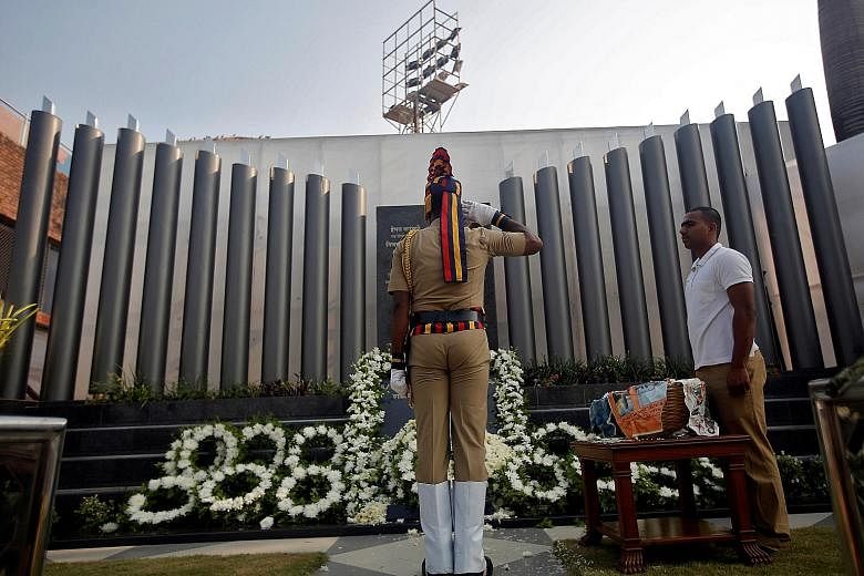 A policeman saluting at a police memorial marking the ninth anniversary of the attacks in 2008, which killed 166 people, in Mumbai, India, yesterday. Barricades were put up across the city and police deployed at every junction amid tightened security