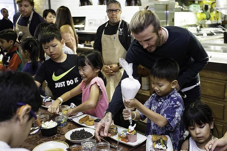 Former Real Madrid and Manchester United superstar David Beckham lending a hand to a young participant at a children's pastry workshop at the The Bird Southern Table and Bar in Marina Bay Sands yesterday. The former England football captain, who is i