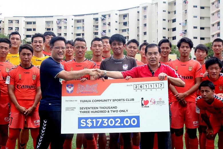 S-League champions Albirex Niigata vice-chairman Koh Mui Tee (in blue) presenting a cheque of $17,302 to Lim Chock Sing, chairman of Yuhua Community Sports Club, yesterday. It was to honour the fifth memorandum of understanding the Japanese club sign