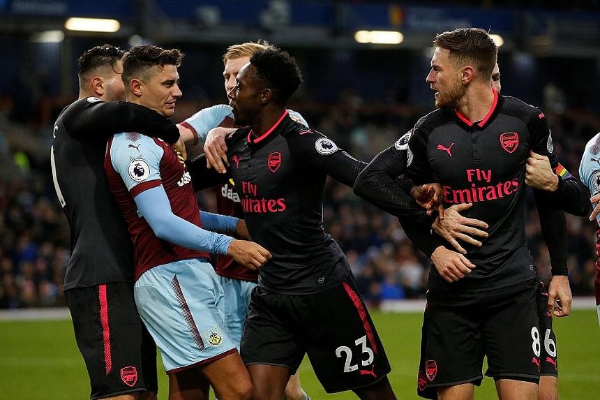 Arsenal's Danny Welbeck (No. 23) steps in to intervene after Burnley's Matthew Lowton clashed with Aaron Ramsey (No. 8) for the latter's part in winning the penalty deep into stoppage time. Arsenal's Alexis Sanchez celebrates after scoring the last-g