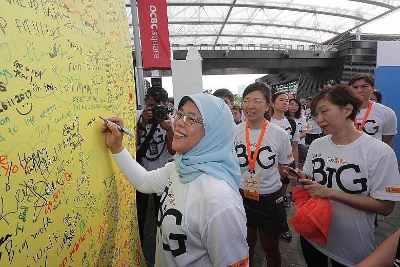 Above: President Halimah Yacob signing off on the National Steps Challenge pledge board yesterday, encouraging everyone to walk and exercise every day. Left: Participants in yesterday's Big Walk, which began and ended at the Sports Hub.