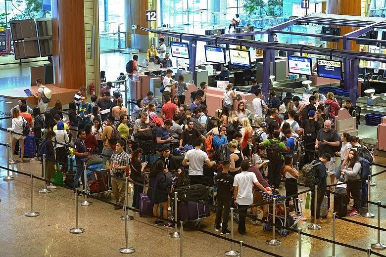 Left: Panels at Changi Airport's T4 informing passengers of cancelled flights to Bali yesterday. Right: At T2, Bali-bound travellers queued to rebook flights and switch destinations.