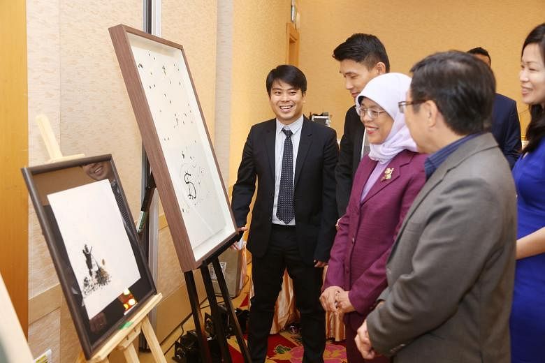 President Halimah Yacob, Parliamentary Secretary for Culture, Community and Youth Baey Yam Keng (second from far left), former minister Mah Bow Tan (in grey jacket), and Tampines GRC MP Cheng Li Hui looking at two paintings yesterday by Raffles Fine 