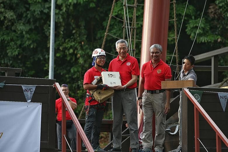OBS instructor Melvin Lam abseiling down while carrying the school's commemorative book at yesterday's event to close the year-long celebration of OBS' golden jubilee. Outward Bound School instructor Melvin Lam presenting Prime Minister Lee Hsien Loo