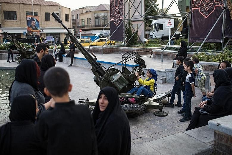An Iranian girl playing with an anti-aircraft gun in Baharestan Square in Teheran, Iran, in September. Seeking to capitalise on a wave of nationalist fervour, the Iranian government is displaying missiles and other weapons in city centres where famil