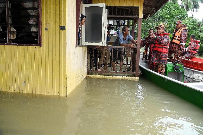 Kelantan's Fire and Rescue Department director Nazili Mohmood (third from right) giving advice to flood victim Nasir Ahmad, 68, while visiting flood-hit areas in Kampung Siput, Meranti, yesterday. The state has at least 8,000 people seeking shelter i