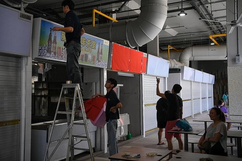 Above: Workers putting up sign boards at the hawker centre at Marsiling Mall yesterday. Left: The last of the stallholders moved out of Old Woodlands Town Centre yesterday.
