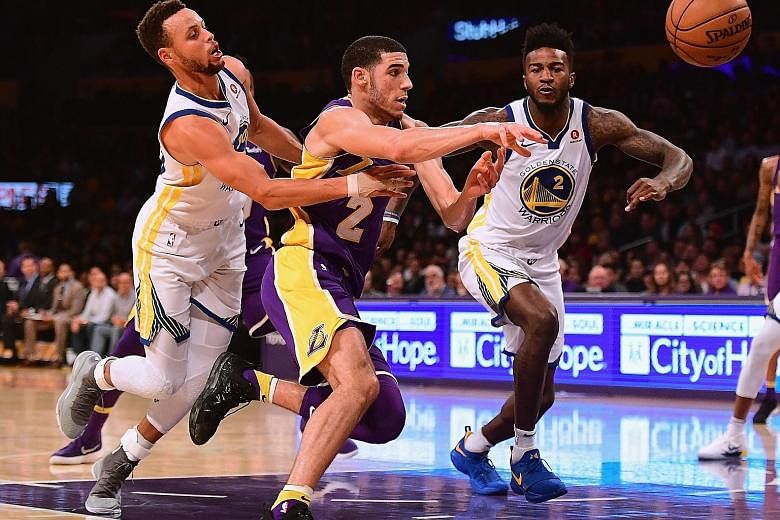 Lonzo Ball of the Los Angeles Lakers loses the ball as he drives to the basket between Stephen Curry (far left) and Jordan Bell of the Golden State Warriors. Despite a slow start, Curry scored 13 of his 28 points in overtime to lead his team to a 127