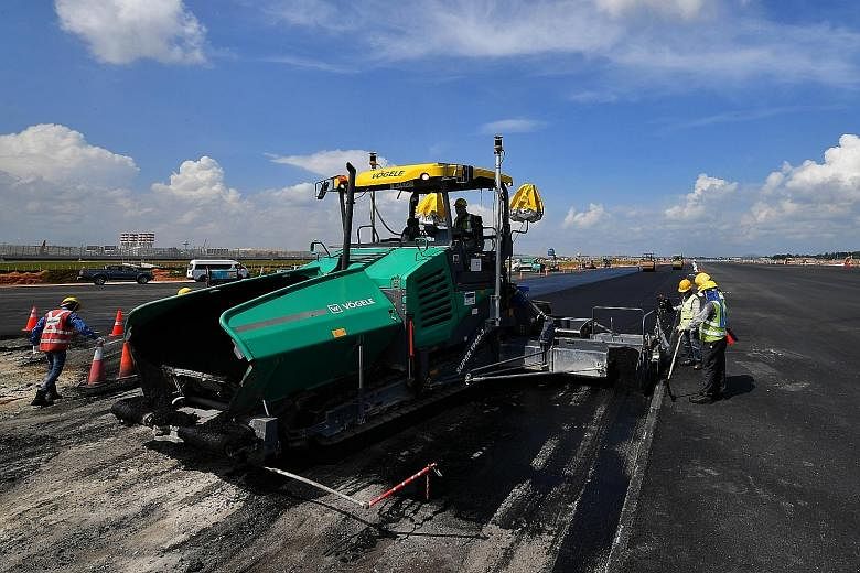 Workers paving a taxiway. It is forecast that Singapore's total air passenger traffic and the number of aviation-related jobs could more than double in 20 years.