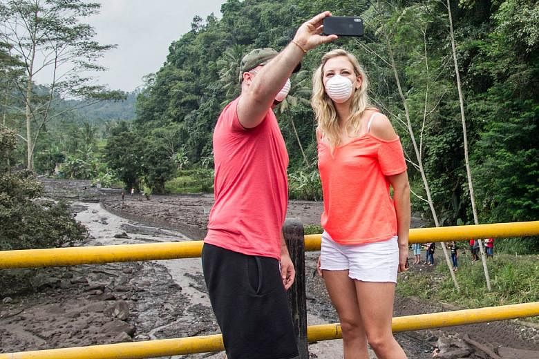 Tourists taking a selfie near the restricted area around Mount Agung in Karangasem, Bali, last Wednesday. Right: Typhoon Hato hit Hong Kong in August. But nasty weather is not keeping visitors away. Right, below: Residents evacuating their homes afte