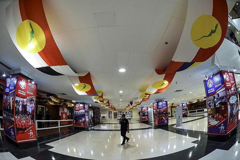 A worker putting the finishing touches to decorations for Umno's General Assembly to be held at the Putra World Trade Centre in Kuala Lumpur this week. The reception area (below) of he Putra World Trade Centre decorated with Umno flags. Umno secretar