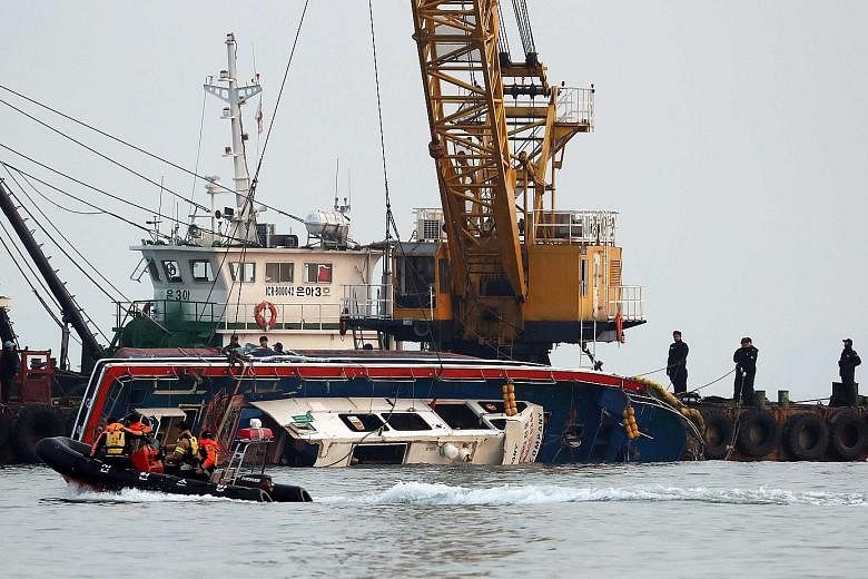 The capsized Seonchang-1 fishing boat being lifted out of the water during a salvage operation in the sea off Incheon, South Korea, yesterday. It collided with a 336-tonne fuel tanker yesterday morning.