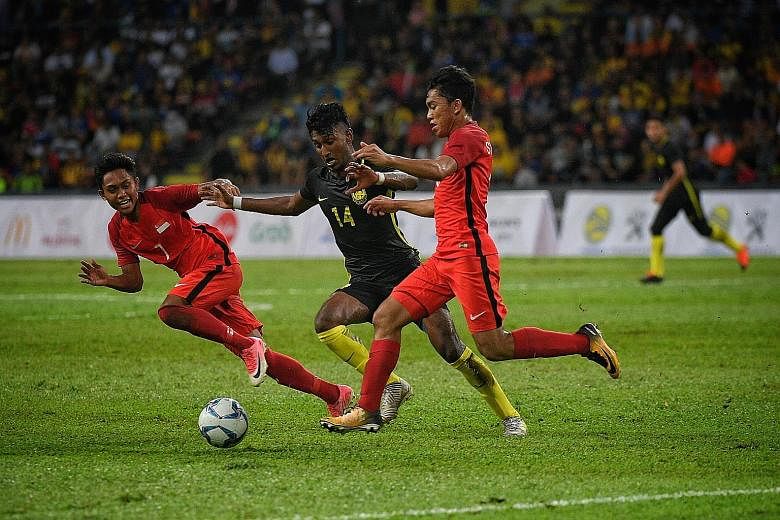 Singapore's Muhaimin Suhaimi (No. 7) and Syahrul Sazali vying for the ball with Malaysia's Syamer Kutty Abba in their SEA Games group match in August. The Young Lions lost 1-2 to their arch-rivals and did not make the semi-finals for the second strai