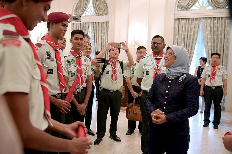 President Halimah Yacob chatting with scouts after an investiture ceremony held at the Istana yesterday. During the ceremony, Madam Halimah was welcomed as the patron of the Girl Guides Singapore and the Singapore Scout Association. She also presente