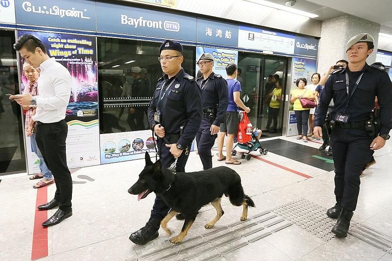 Senior Staff Sergeant Wong Wenxiong with his dog Esso and Sergeant (NS) Bryant Choo patrolling at Bayfront MRT station. Police dogs are leashed and will not approach a person without a command from their handler.