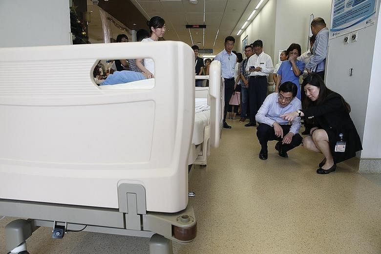 Finance Minister Heng Swee Keat being shown a bed transporter at Changi General Hospital. The innovation makes it easier to move beds with patients lying on them, and cuts the risk of staff getting injured on the job.