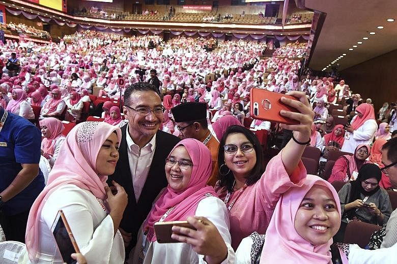 Umno vice-president Hishamuddin Hussein posing for a picture with Puteri Umno members during the Puteri Umno General Assembly at the Putra World Trade Centre yesterday. Renewing Umno's appeal to a sorely fractured Malaysian electorate is the top prio