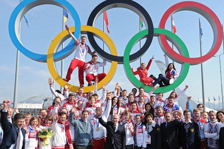Russian President Vladimir Putin (front) with Russian athletes after their table-topping achievements at the Sochi Games. They have since been stripped of 11 medals.