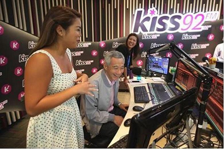 Prime Minister Lee Hsien Loong tried his hand at deejaying during a visit to Singapore Press Holdings (SPH) radio station Kiss92 FM yesterday. Here, he is flanked by DJs Charmaine Yee (far left) and Carol Smith. "DJs have a demanding job - they have 