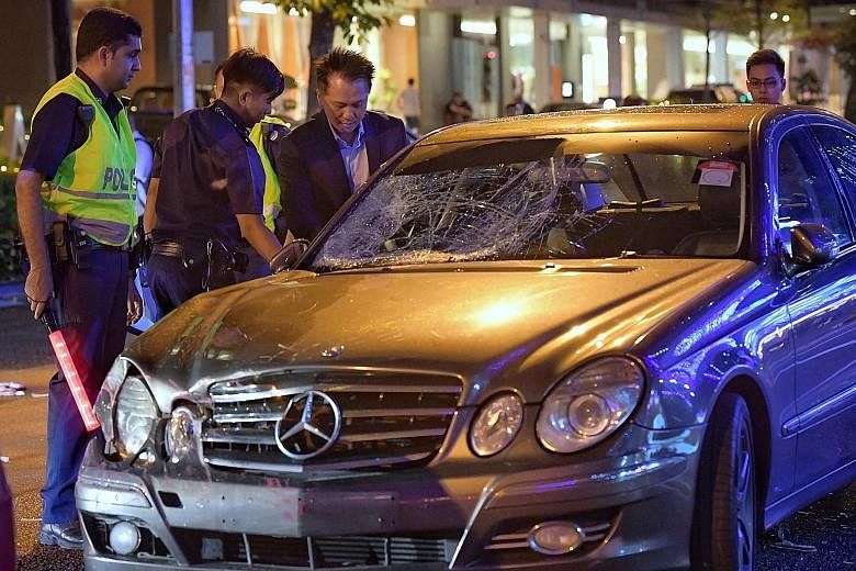 The driver of the Mercedes-Benz, accompanied by police officers, at his car after the accident outside Amara Hotel yesterday. Passers-by helping pedestrians who were injured during the accident, which happened at about 6.30pm, during rush hour.