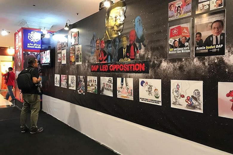 The board of posters at Umno's annual assembly in Kuala Lumpur consists of 20 caricatures and anti-opposition images that criticise the four-party Pakatan Harapan opposition alliance.