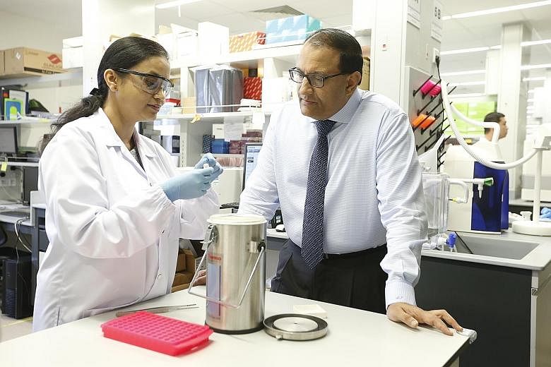 Dr Lakshmi Ramakrishna explaining to Minister for Trade and Industry (Industry) S. Iswaran how patient samples preserved in liquid nitrogen canisters are the start point for research projects at a lab in SingHealth Academia, located in SGH.