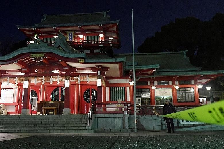 A policeman standing guard at the Tomioka Hachimangu shrine in Tokyo yesterday. According to the police, the chief priestess of the shrine was killed with a Japanese sword on Thursday by a man said to be her younger brother, who then killed a woman w