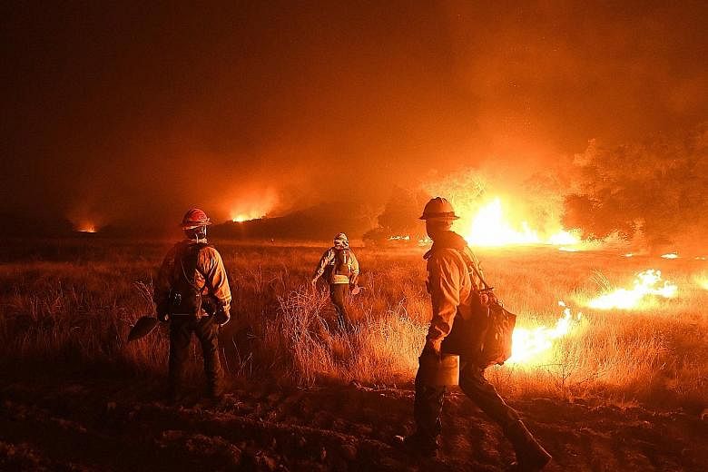 Firefighters lighting backfires as they attempt to contain the Thomas Fire, which continues to burn in Ojai. The blaze, which is the largest of the wildfires that have swept across southern California, has blackened 60,000ha in Ventura County and was