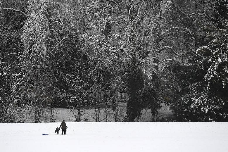 People walking on the snow in a park in High Wycombe, 48km north-west of London, yesterday. Amber weather warnings have been issued after heavy snow affected large areas of Britain. Cars moving on the snow-covered highway A25 in Godewaersvelde, north