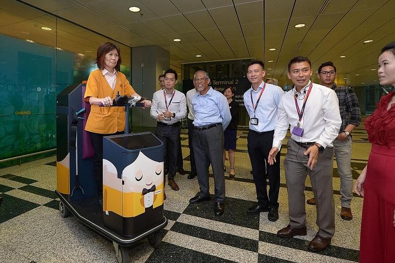 Mr Masagos Zulkifli (centre) watching a demonstration of how a battery-operated housekeeping cart is used at Changi Airport's Terminal 3 yesterday. The cart helps to reduce fatigue and enhance productivity.