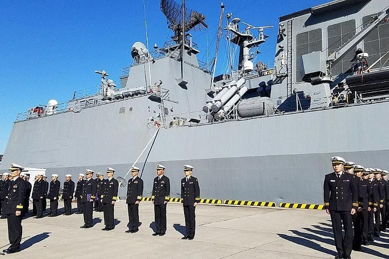 Soldiers at a welcome ceremony for South Korea's destroyer the Ganggamchan and logistic supporting vessel the Hwacheon in the Japanese port city of Yokosuka in Kanagawa prefecture yesterday, as the US, Japan and South Korea kicked off a two-day joint