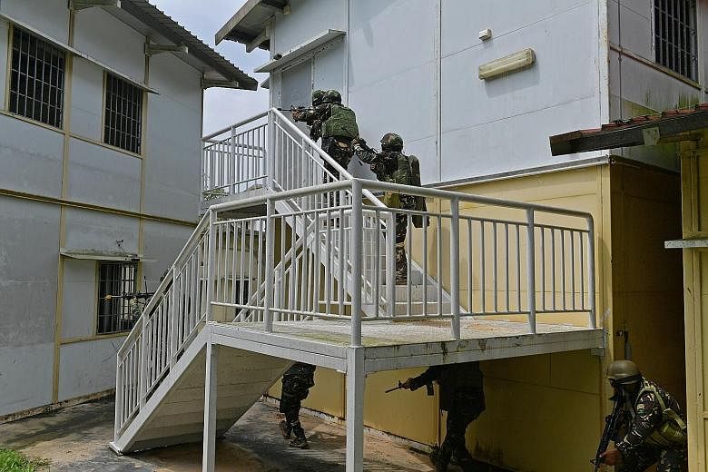 Philippines Army personnel doing section-level urban operations drills and capturing a building at the Murai Urban Training Facility. A soldier using a breaching tool to break into a building during the exercise.