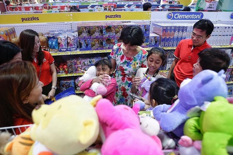 Sisters Nur Qanitah Husna Md Saad, seven, and Nur Kamirah A'Lawiyyah, 11, were among 50 children who picked out new toys yesterday at Toys 'R' Us in Parkway Parade. Kamirah chose a giant teddy bear and two keychains for herself and her mother, while 