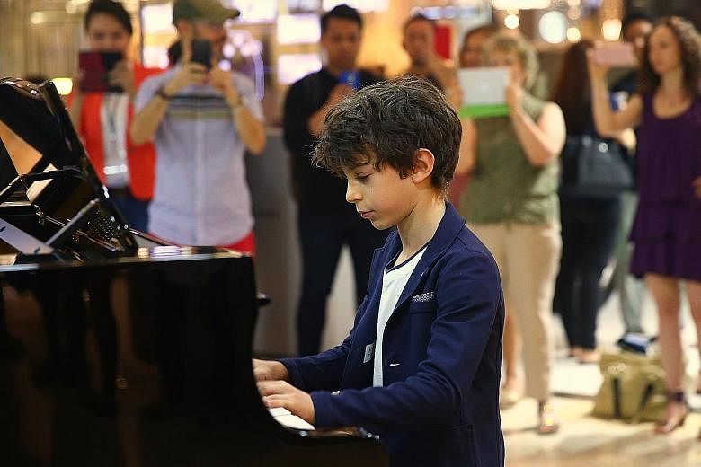 Eleven-year-old Jesse Collins playing his own composition in the piano marathon at Ion Orchard yesterday. Proceeds from the 13-hour charity marathon will go to The Business Times Budding Artists Fund, which provides arts training to young people from