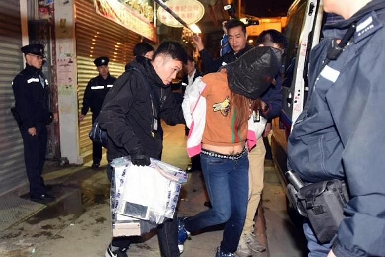 The 37-year-old suspect being led away by police on Sunday after they discovered her daughter's remains in the flat. The woman, identified by police as a mainland Chinese woman surnamed Cao, was found in a delirious state after police had forced thei