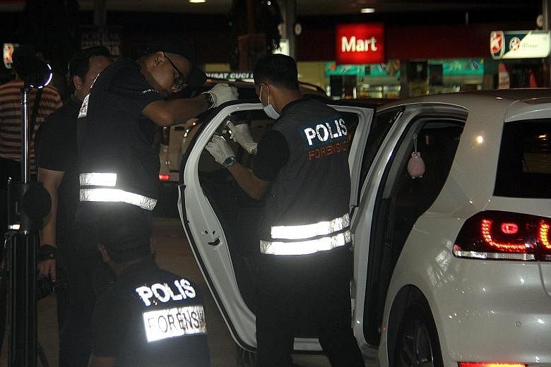 Officers from the forensic unit checking the car owned by a 44-year-old man who died after he was stabbed and then run over twice by four assailants in a BMW at a Shell petrol station in Jalan Sri Pelangi on Sunday.