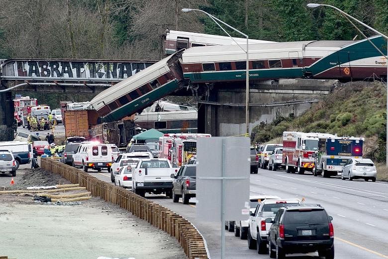 Emergency personnel near the derailed Amtrak train in DuPont, Washington. Thirteen of the train's 14 cars jumped the tracks. The scene at a portion of the Interstate I-5 highway after an Amtrak high-speed train derailed from an overpass on Monday. Th
